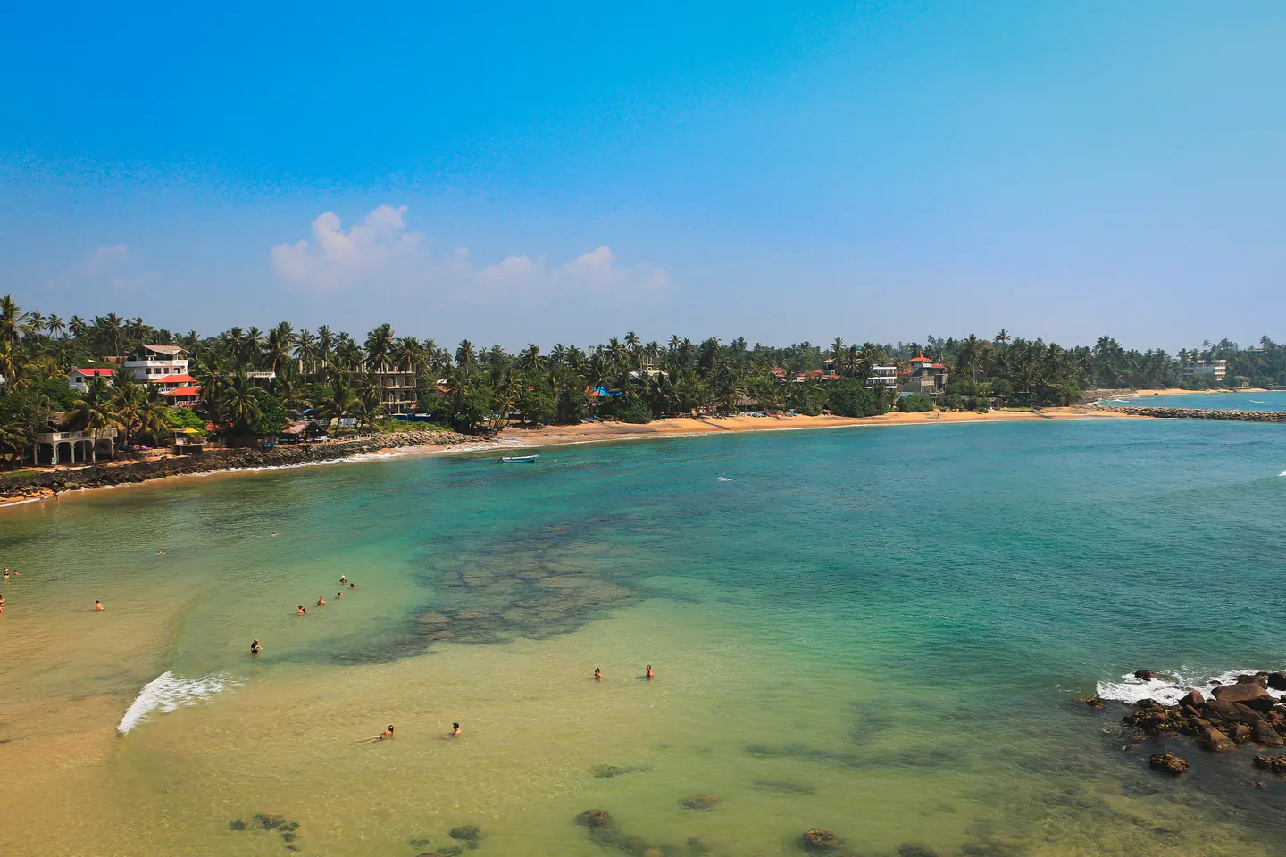 Aerial view of turquoise water and palm-lined Mirissa beach in Sri Lanka